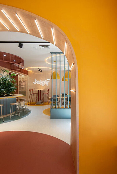 Modern bistro interior with arched entrance, blue bar counter and colourful furniture, seating and tables.