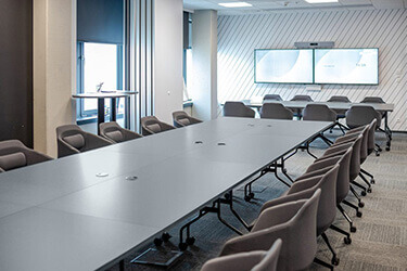 Modern conference room with grey office furniture: large table and chairs on wheels.
