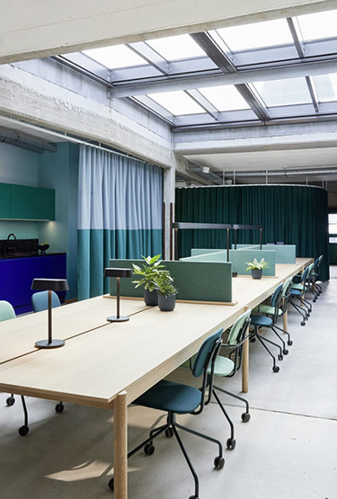 Coworking space with a long table and upholstered chairs on wheels in a marine colour scheme.