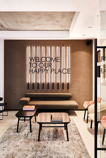 Cosy waiting room with brown sofa, black coffee tables and neon sign.