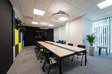 Conference room with modern table, chairs with armrests and wall panels.