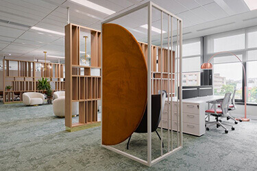Open plan office space with white desks, ergonomic chairs and partitions to zone the interior.