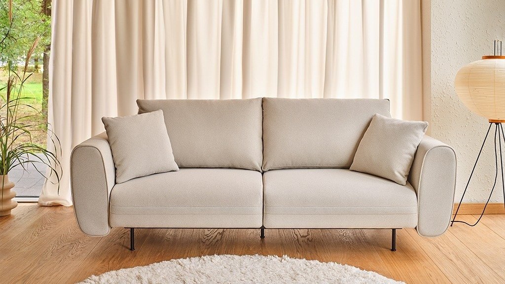 Orange Lotus two-seater sofa with cushions, set against a yellow wall in a bright living room