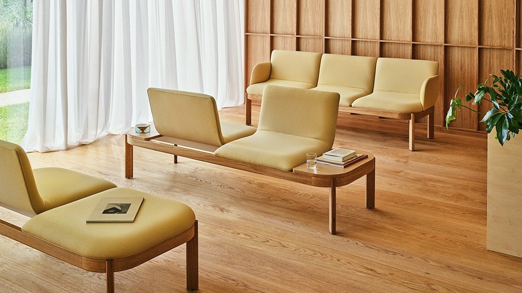 Arrangement of beige sofas on wooden frames in a space finished with wood panels