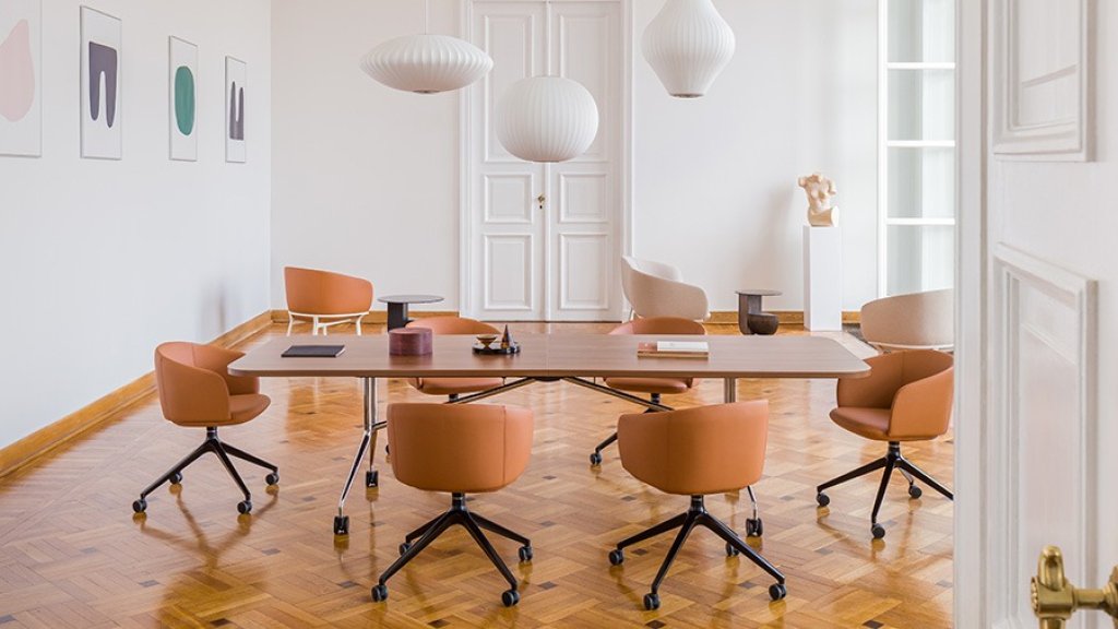 Conference room with a large wooden table and six brown chairs on castors.
