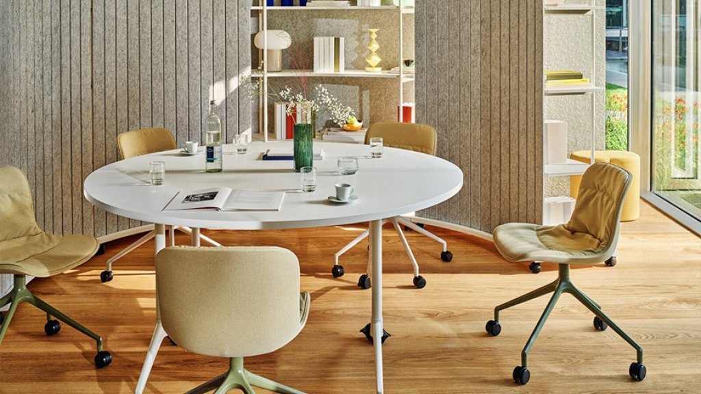 Round white conference table with beige and yellow chairs in a modern interior.