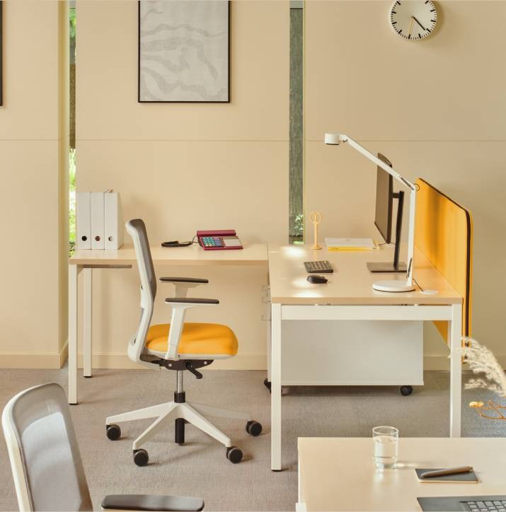 Scrivania bench Ogi Y con pannello acustico giallo, ambientata in un ufficio moderno
