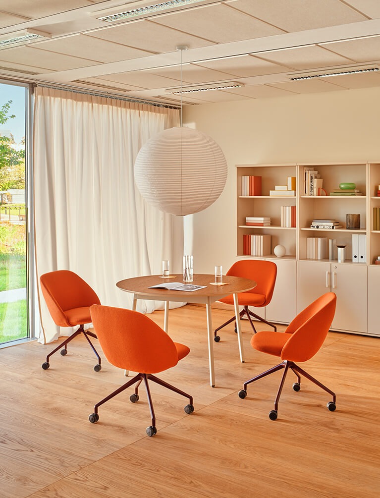 Orange Paralel conference chairs on castors at a round table in a bright interior.