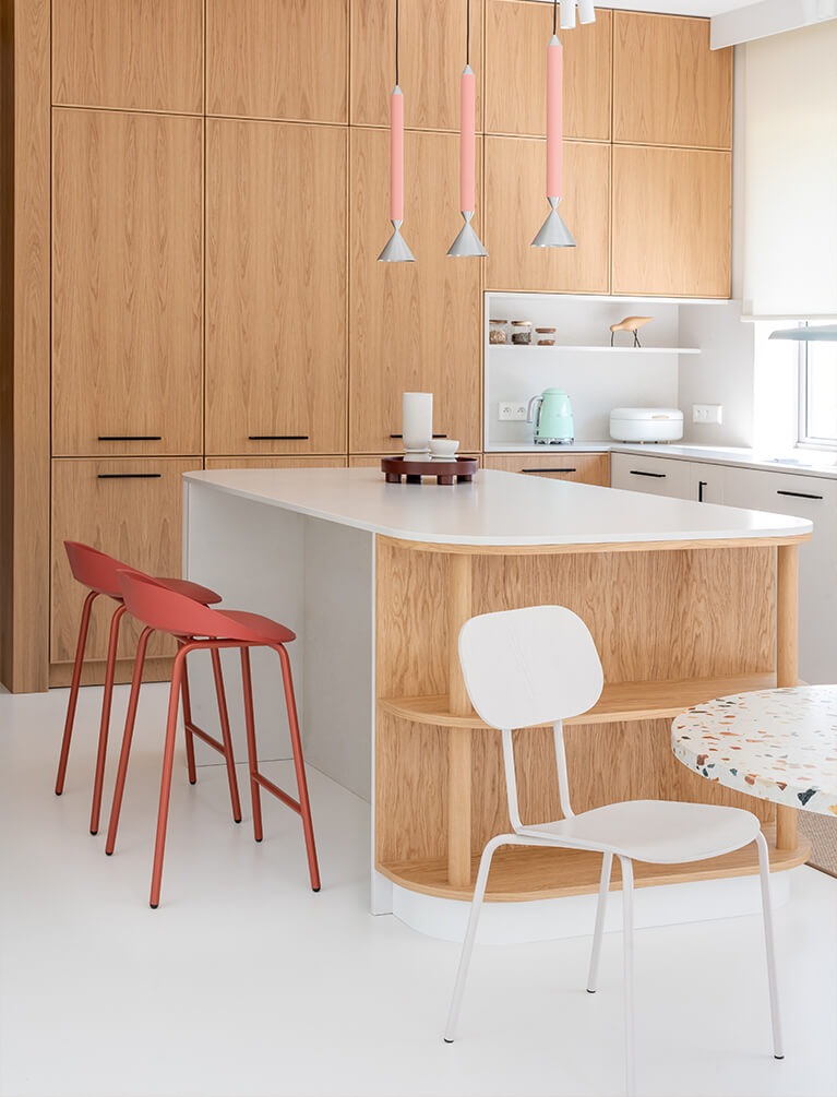 Chaises et tabourets de salle à manger modernes blancs et rouges près de l'îlot de cuisine dans un intérieur clair et aéré