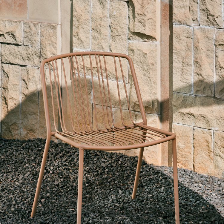 Silla metálica beige Bris sobre fondo de pared de piedra