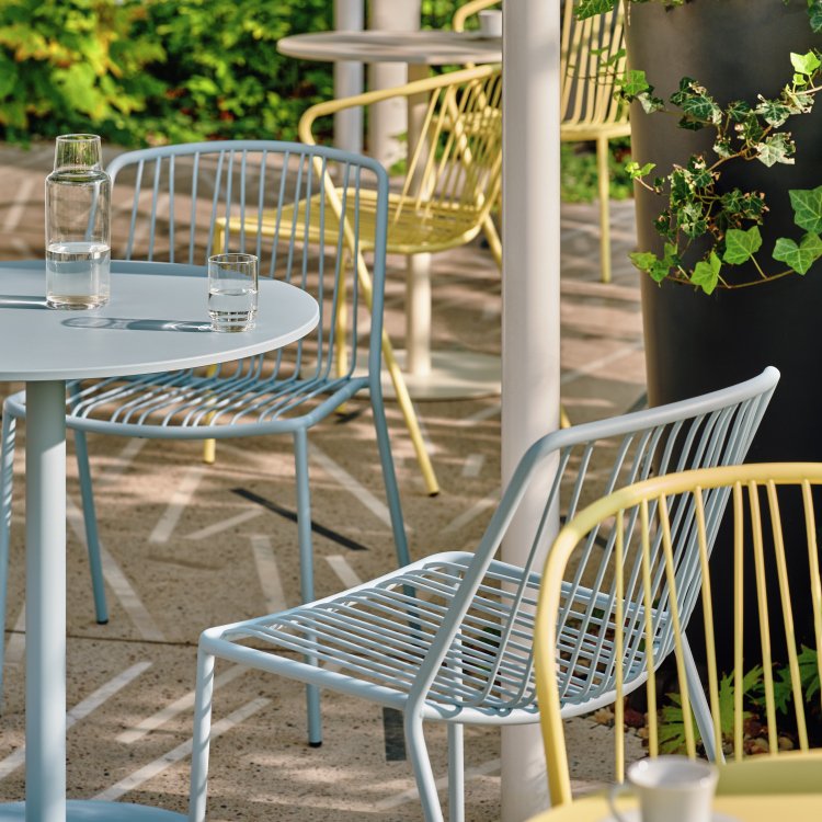 Arredamento del patio con sedie Bris blu e giallo pastello e tavolini rotondi
