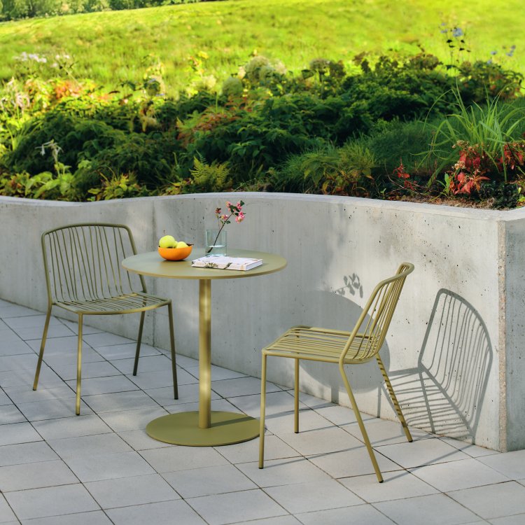 Terrace space arranged with green Bris chairs and a round table.