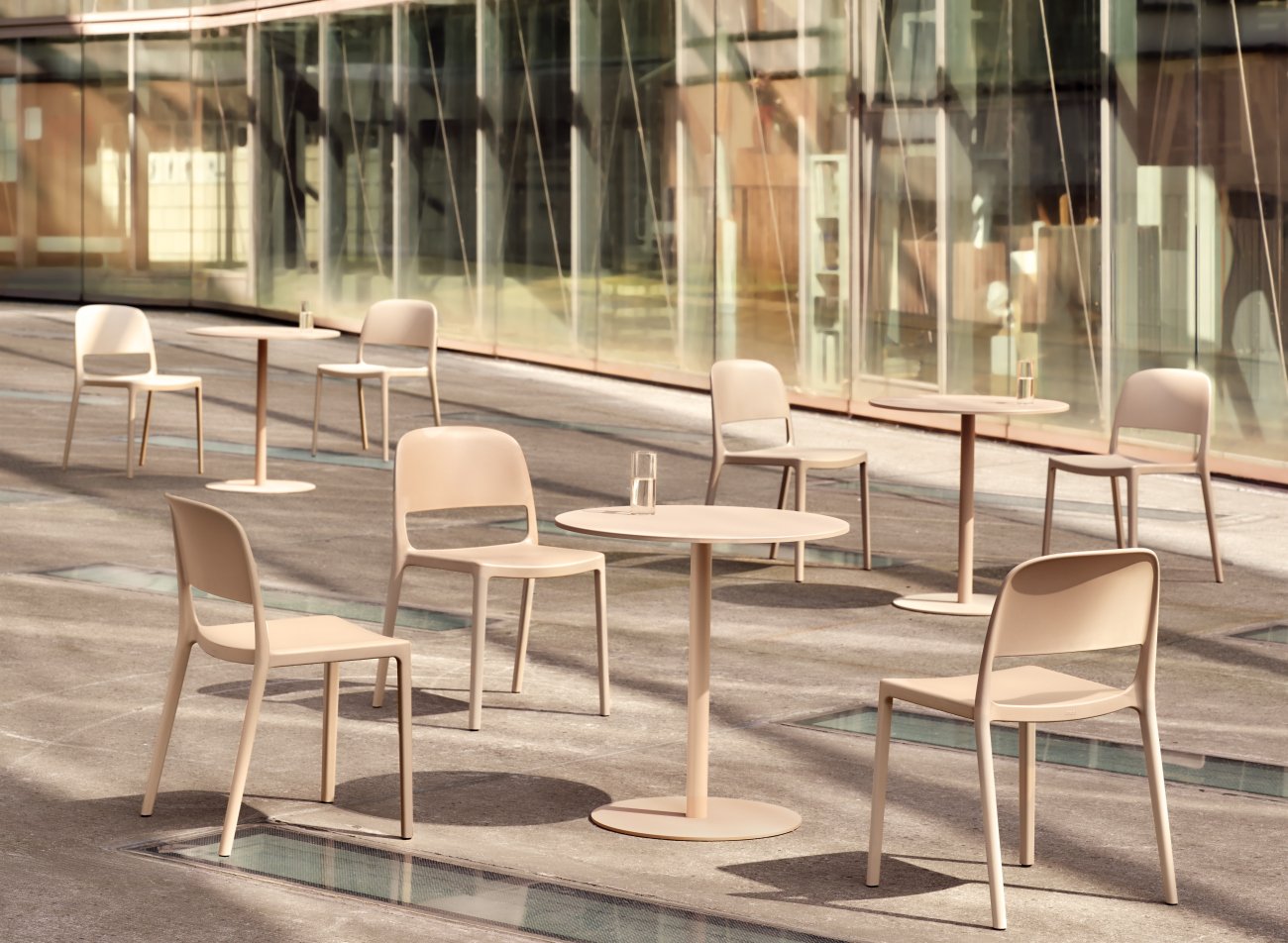 Chaises en plastique beiges Blendy et tables de la même couleur disposées sur la terrasse