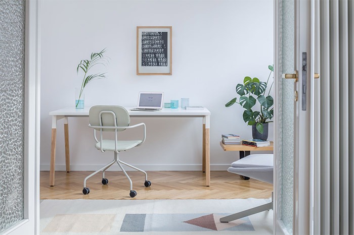 Espace de travail à domicile avec un petit bureau et une chaise blanche à roulettes