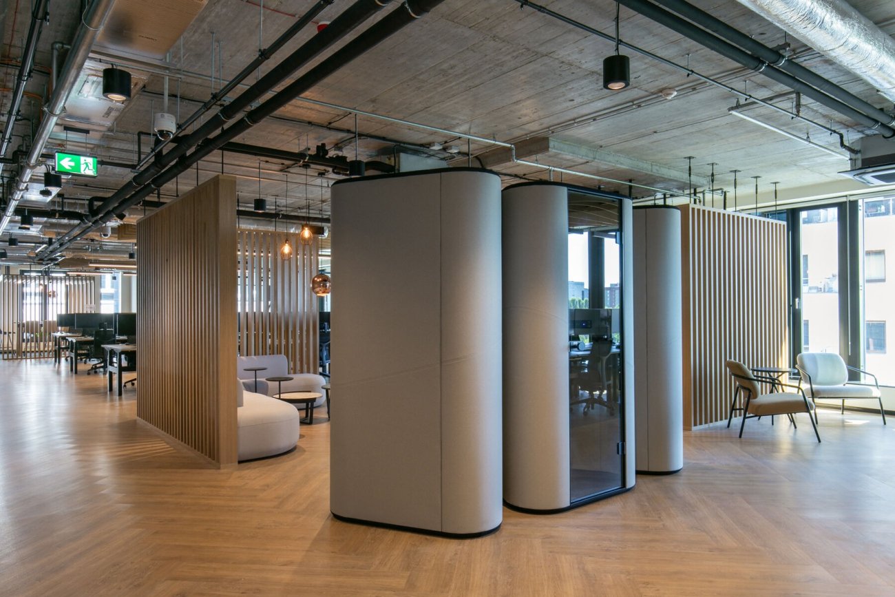 Grey upholstered acoustic booths in an open-plan office space
