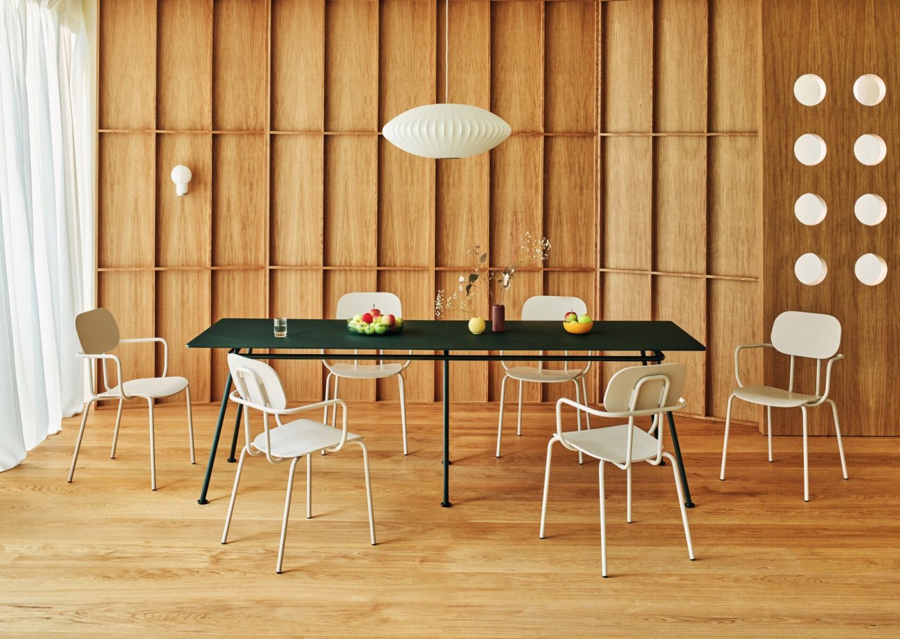 Espace fini en bois avec des chaises en contreplaqué blanc et une table vert foncé.