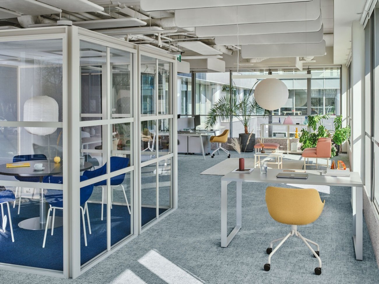 Przestrzeń biurowa typu open space z przeszkloną budką do spotkań
