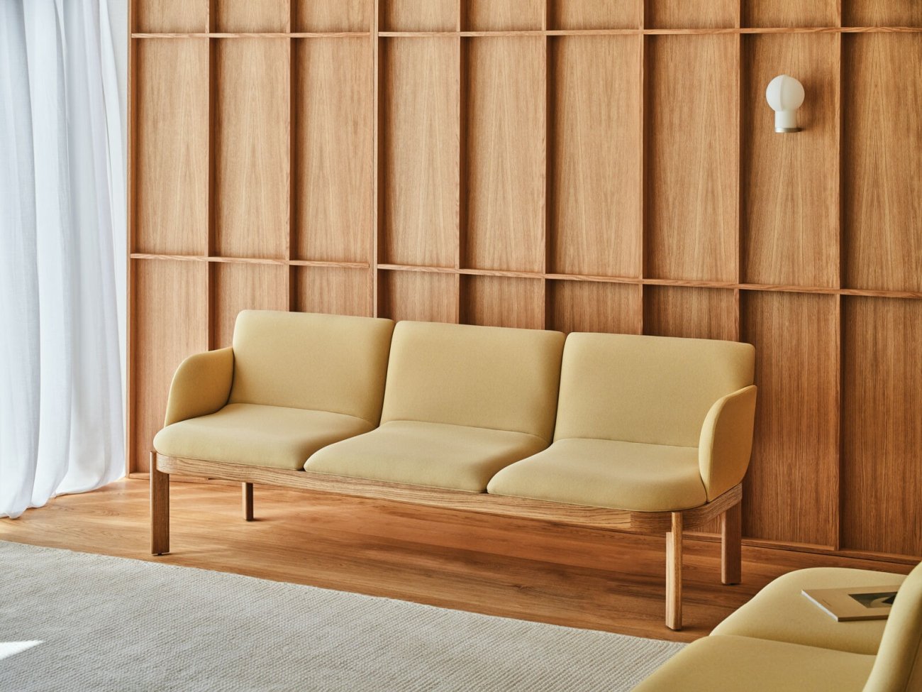 Canapé Ramp avec revêtement jaune et structure en bois dans un espace fini avec des panneaux