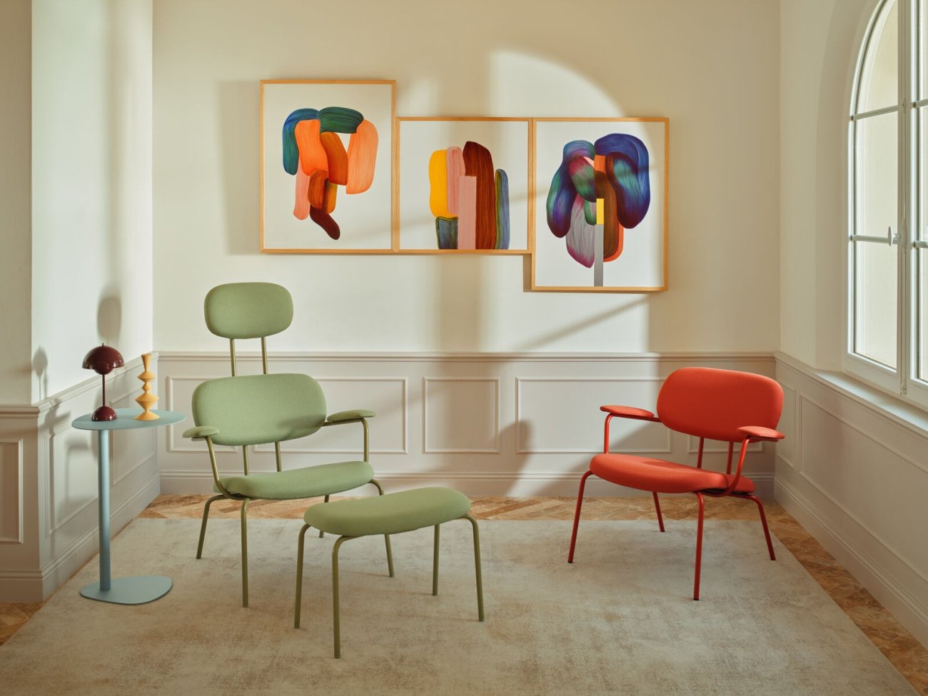 Strefa odpoczynku w biurze wyposażona w zielony i czerwony fotel z tapicerką oraz podnóżek