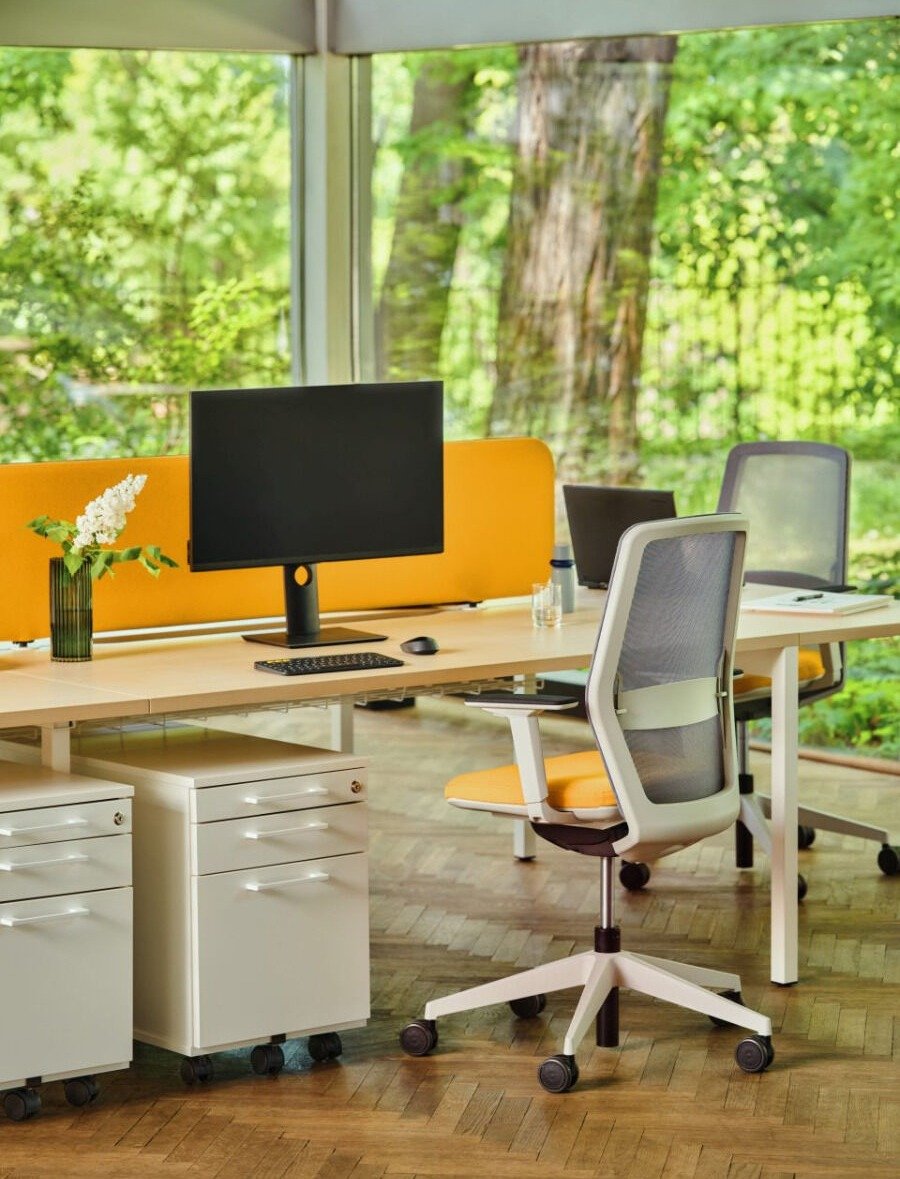 White office drawer unit with drawers and a lock, placed next to a desk in an open-plan office