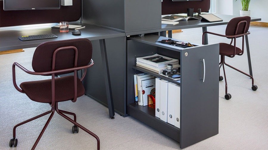 Graphite office storage unit with a door and shelves for binders under the desk