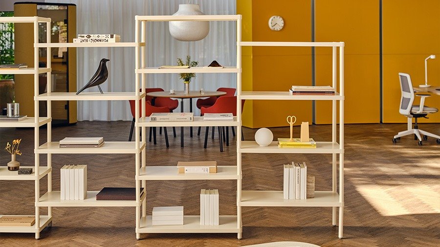 Étagères modulaires claires servant de séparation de bureau, avec livres et objets déco