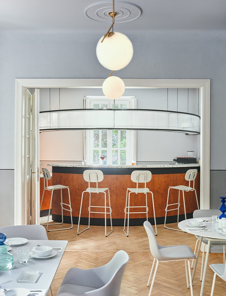 White New School bar stools with backrests set against a rounded bar top.
