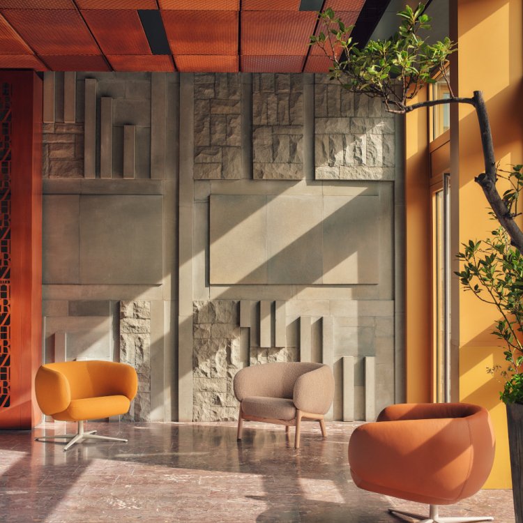 Beige, yellow and brown Grand Grace armchairs in a sunny space by a concrete mosaic