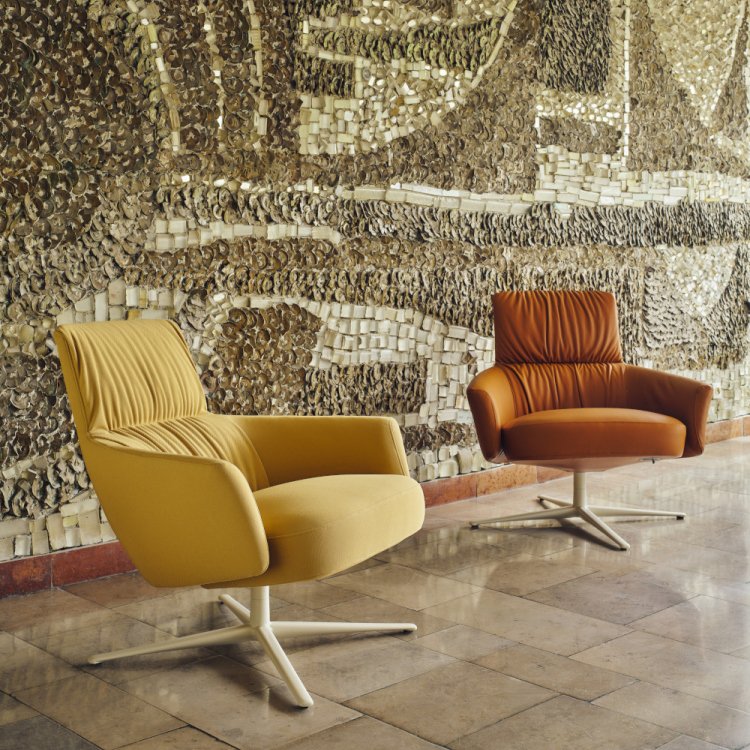 Beige and brown Toro armchairs set in front of a wall with stone mosaic