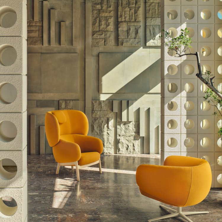A high and low Grand Grace armchair arranged by a sculptural wall