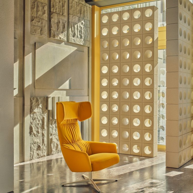 Yellow Toro armchair with wide headrest set against an architectural background