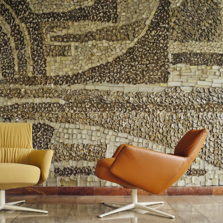 A titled brown leather Toro armchair in front of a stone mosaic