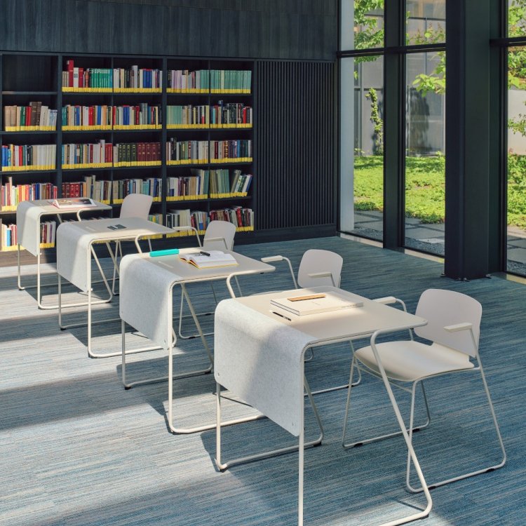 Small grey desks and conference chairs arranged in a library space