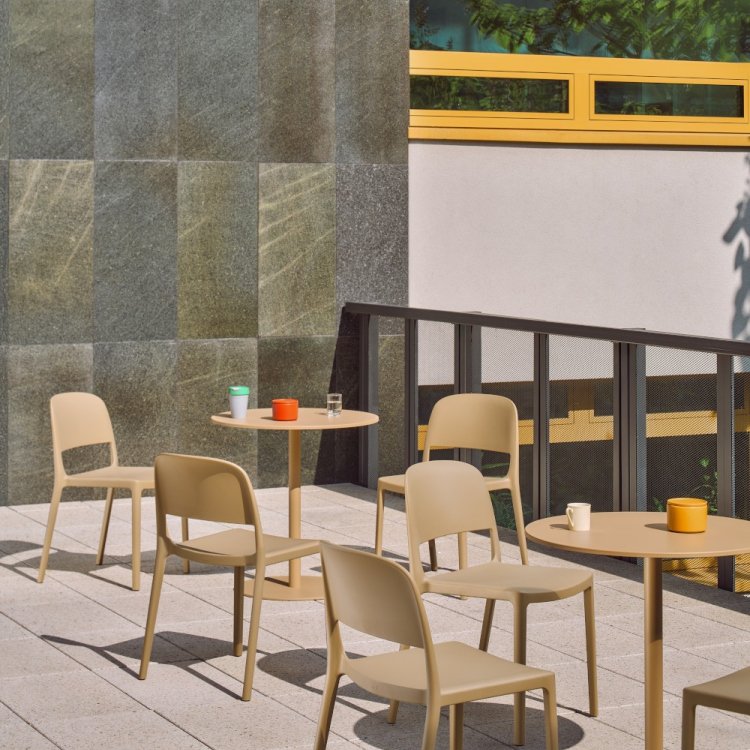 Beige plastic Blendy chairs and round Bolt tables on a sunny terrace