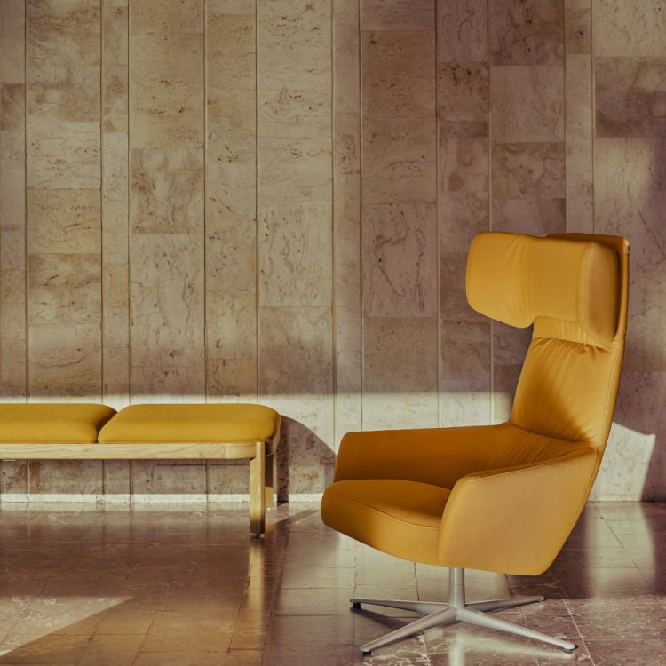 Yellow armchair with wide headrest set against a stone wall