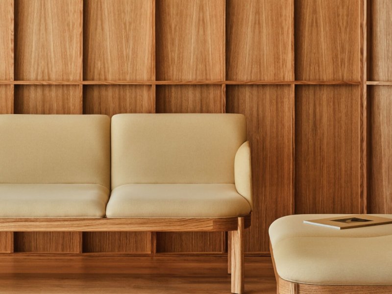 Leuchtend gelbes Sofa vor einer Holzwand