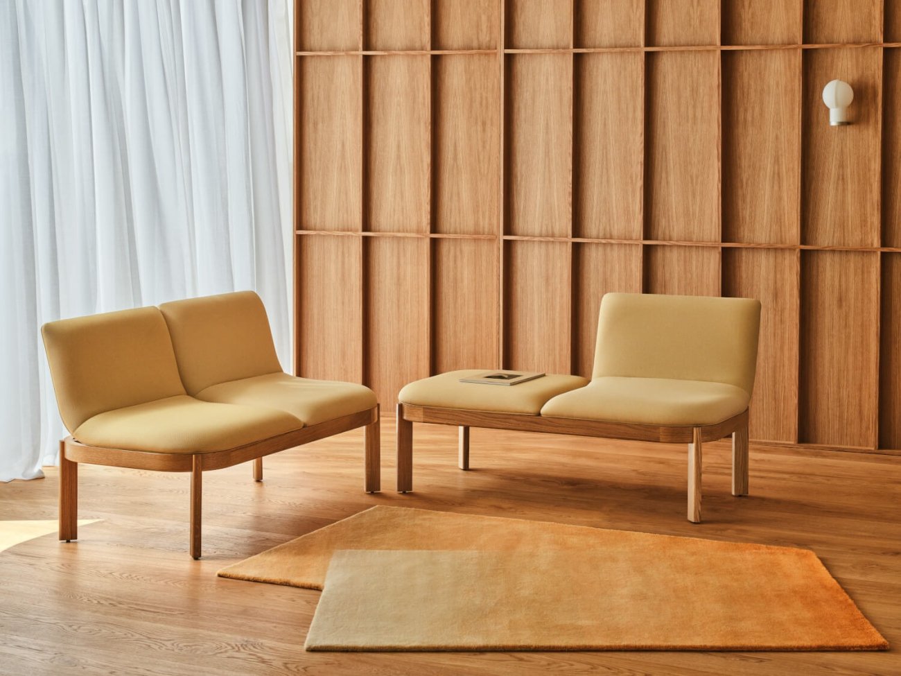 Canapés jaune vif sur des bases en bois, disposés avec un tapis assorti