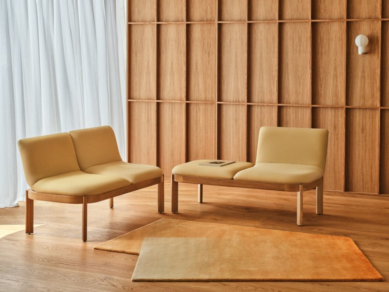 Leuchtend gelbe Sofas auf Holzsockeln, dazu ein passender Teppich