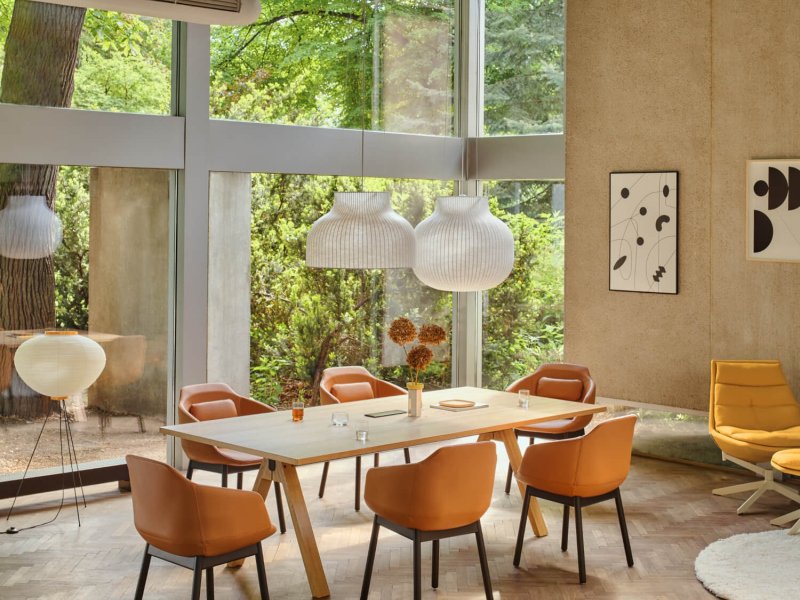 Brown chairs and wooden Viga table set in a modern conference room with high windows
