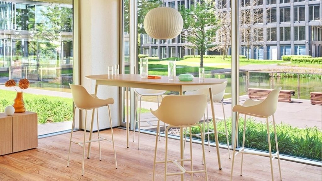 Modern plastic kitchen and bar hockers with backrest at a round table in a glazed interior.
