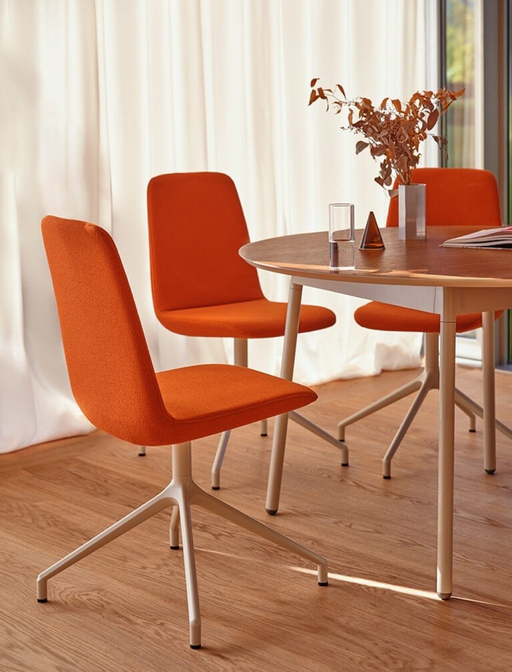 Ulti upholstered conference chairs in orange at a round table.