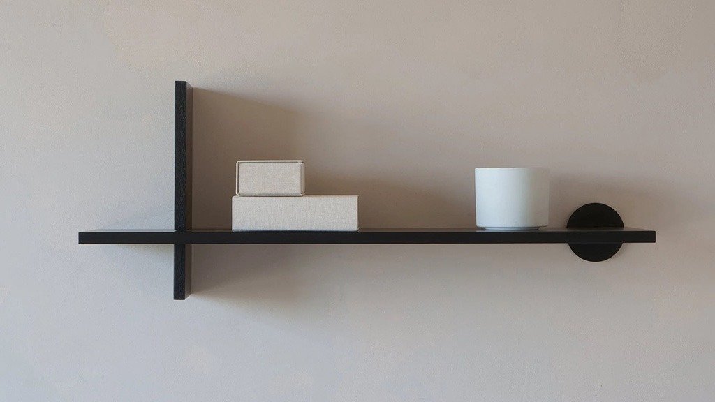 A black wall shelf with a simple design, featuring a decorative mounting bracket
