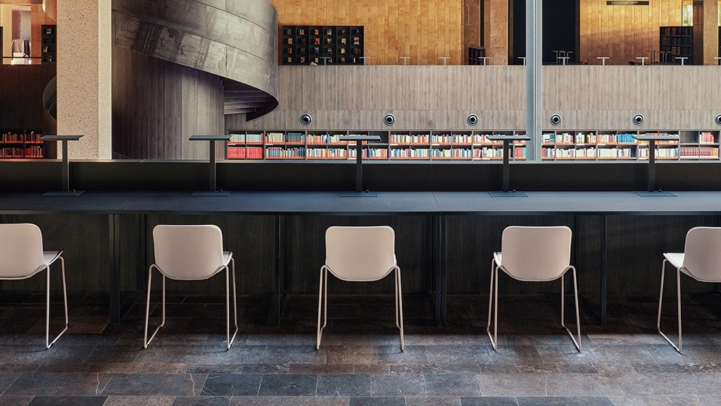 Sedie in plastica disposte una accanto all'altra nello spazio della biblioteca