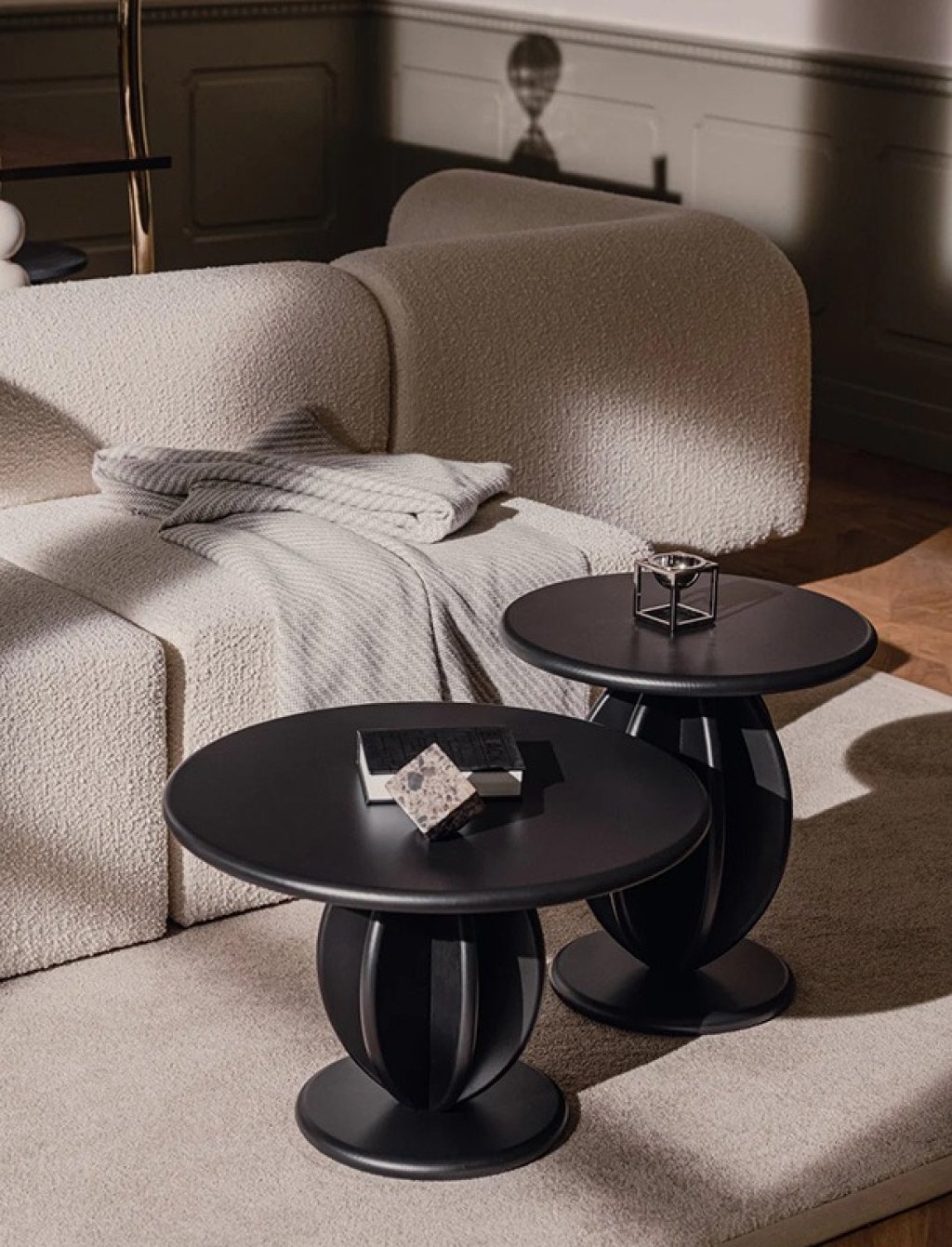 Set of two black coffee tables with round tops and sculpted bases