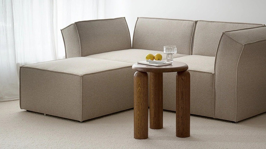 A small wooden side table on three round legs, placed next to the sofa